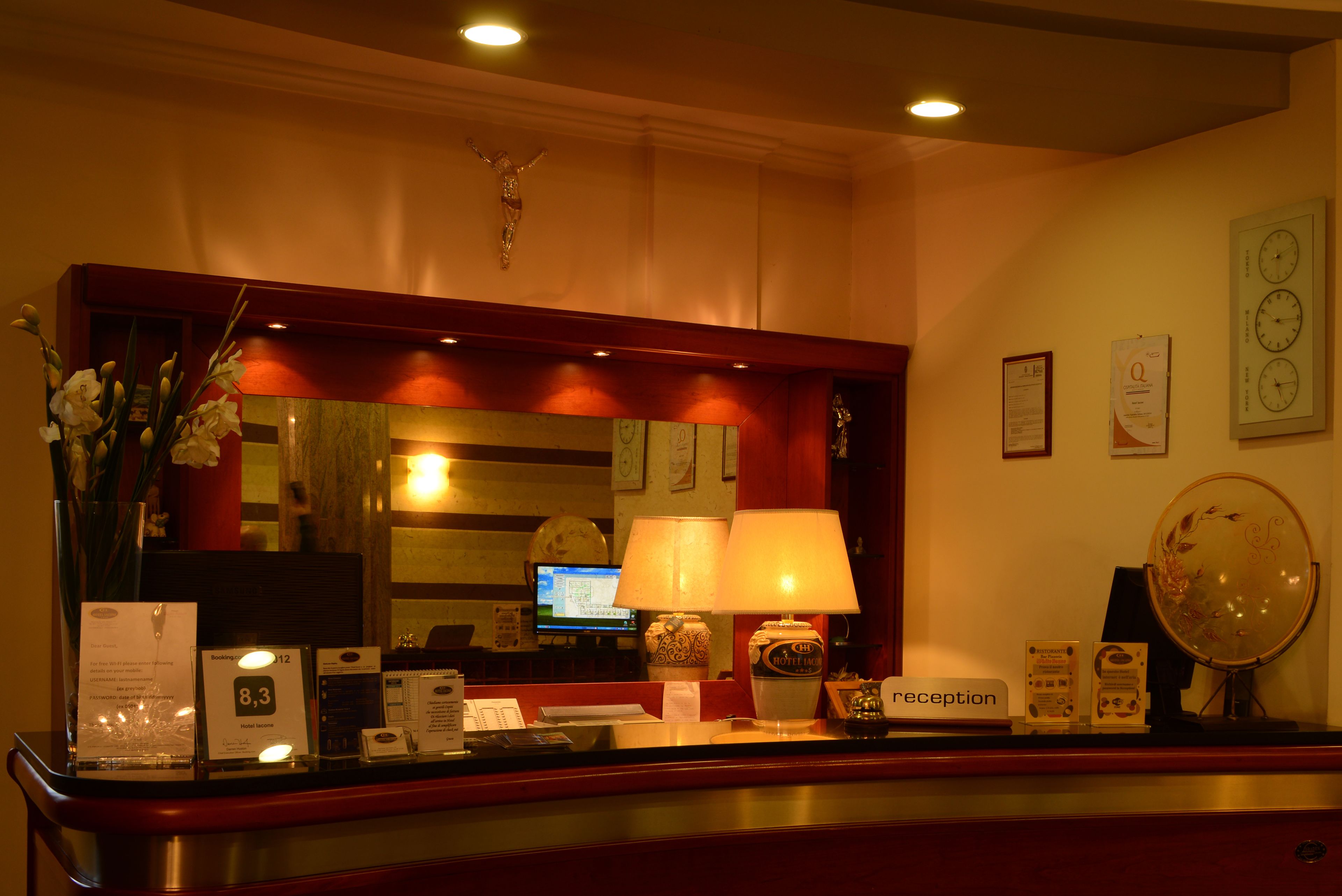 A hotel reception desk with a mirror, a clock, and a reception sign.