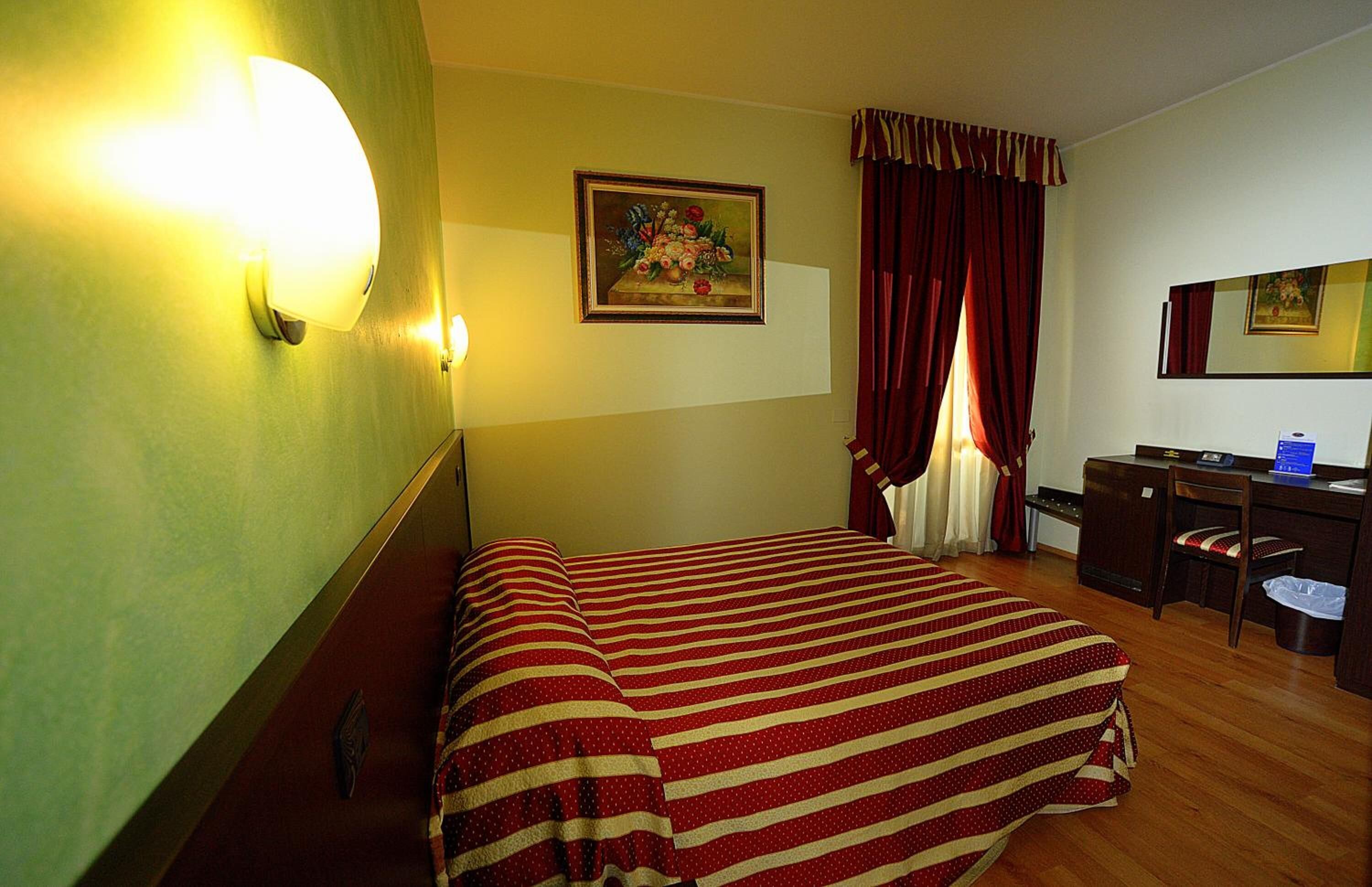 Ein Hotelzimmer mit Bett, Schreibtisch, Stuhl und einem Bild an der Wand.