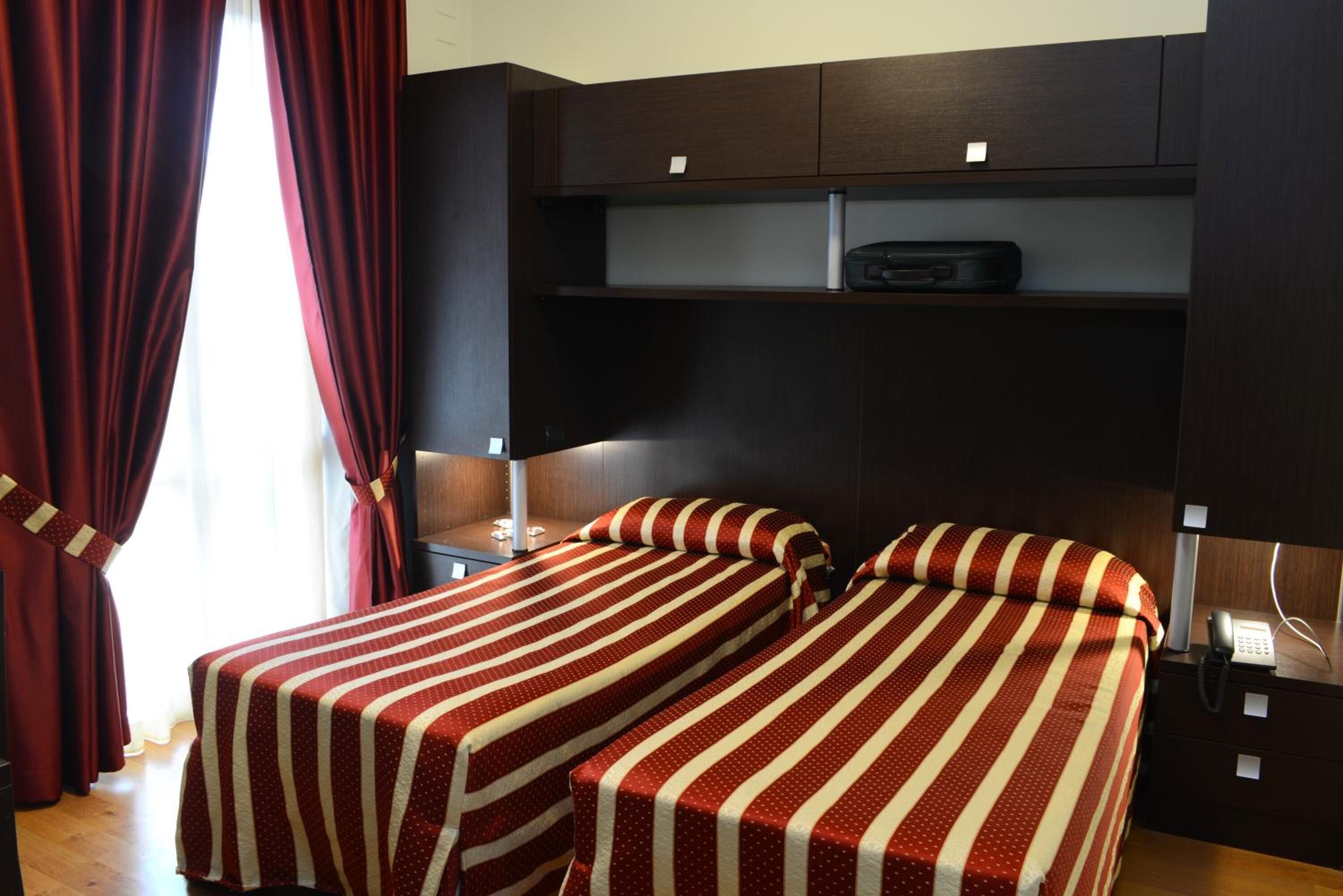 A hotel room with two beds, a desk, and a wardrobe.