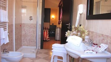 Un baño con ducha, bidé, lavamanos y espejo.