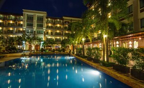 Un hotel con piscina, varios balcones y abundante vegetación.