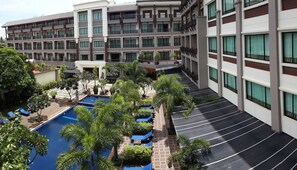 Un hotel con piscina, mobiliario exterior y un jardín bien cuidado.