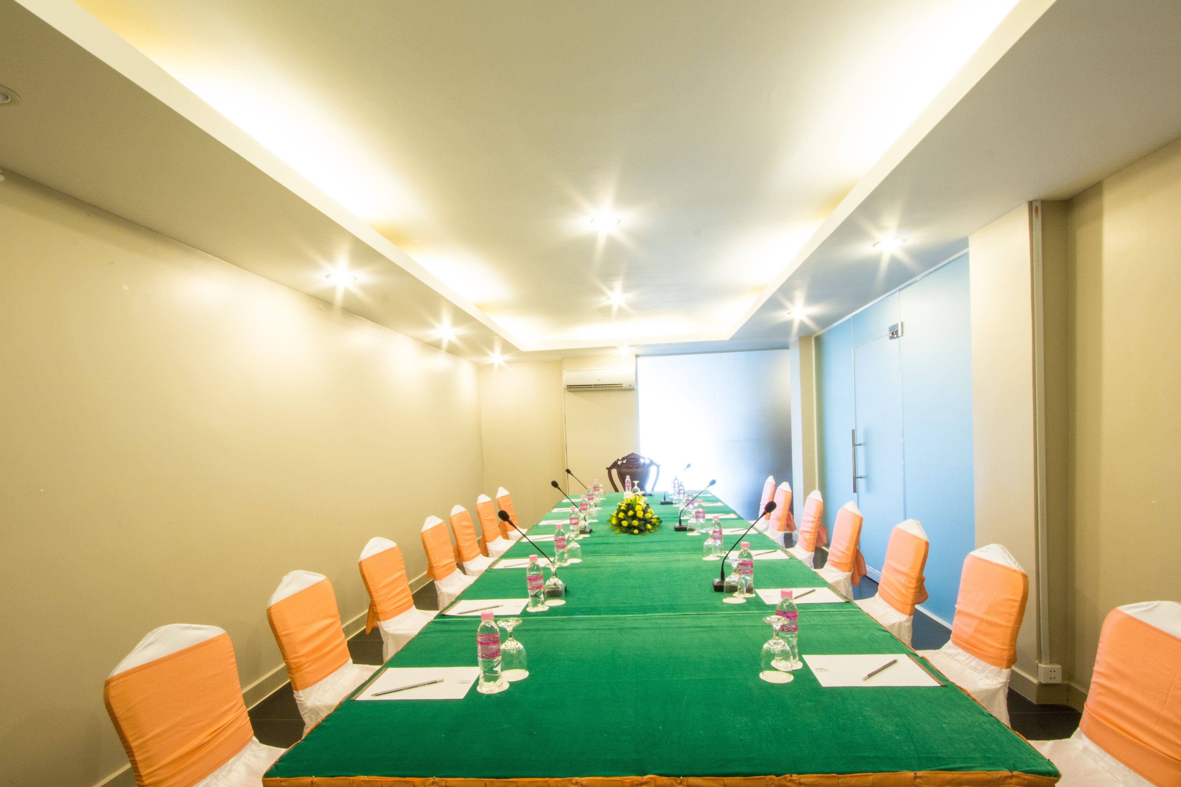 A conference room with a long table, chairs, and microphones.