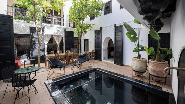 A courtyard with a swimming pool, outdoor seating, and potted plants.