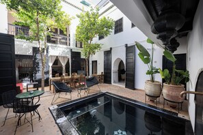 Un cortile con piscina, area relax all'aperto e piante in vaso.