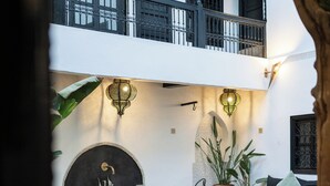 A courtyard with a dining area, a pool, and a lounge with a sofa and chairs.