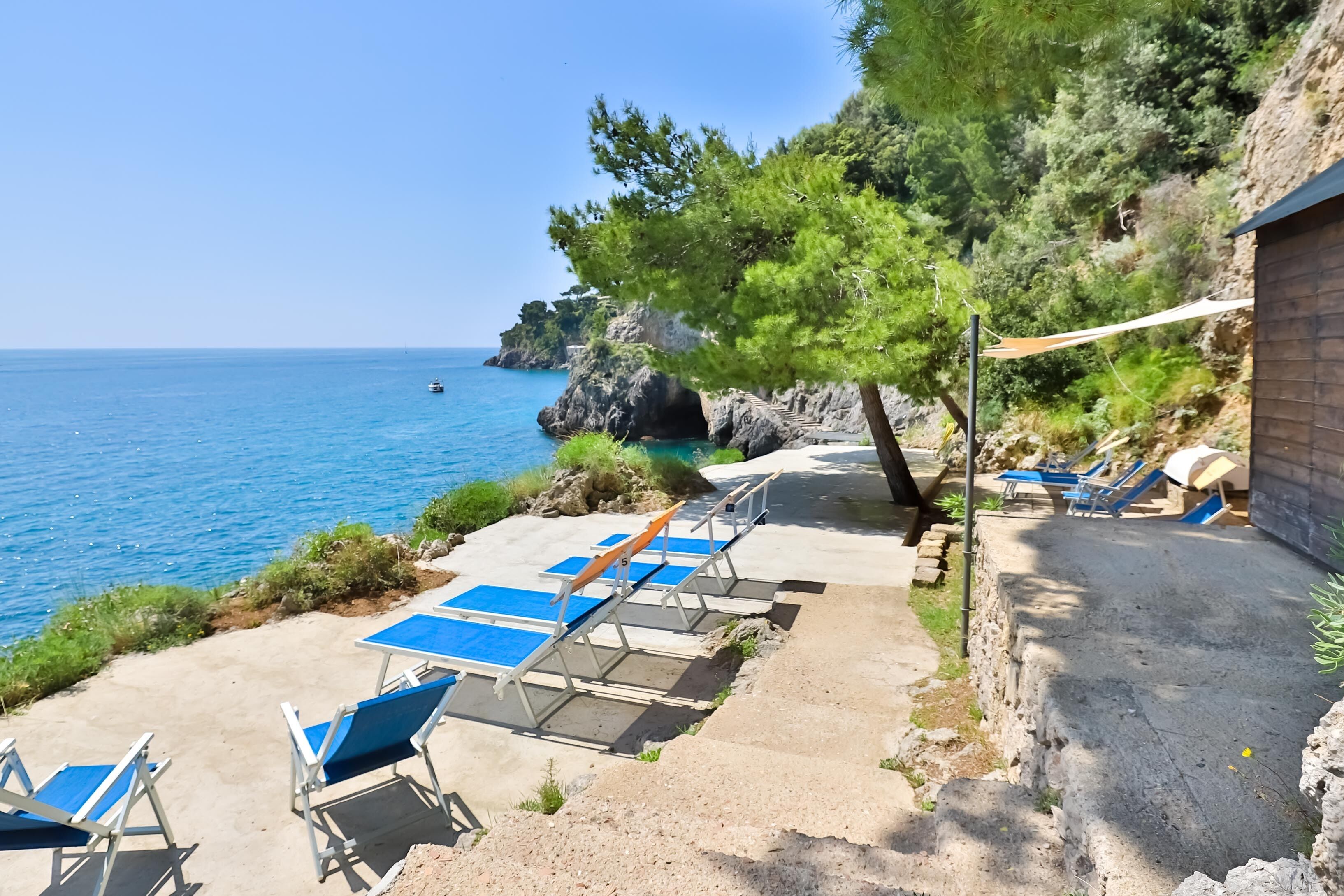 Une zone côtière avec des chaises longues bleues et une vue dégagée sur la mer.