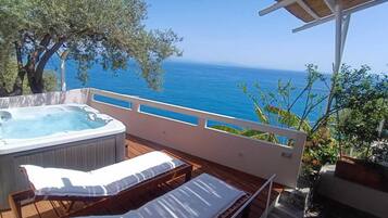 Ein Balkon mit Whirlpool, Liegestühlen und Meerblick.