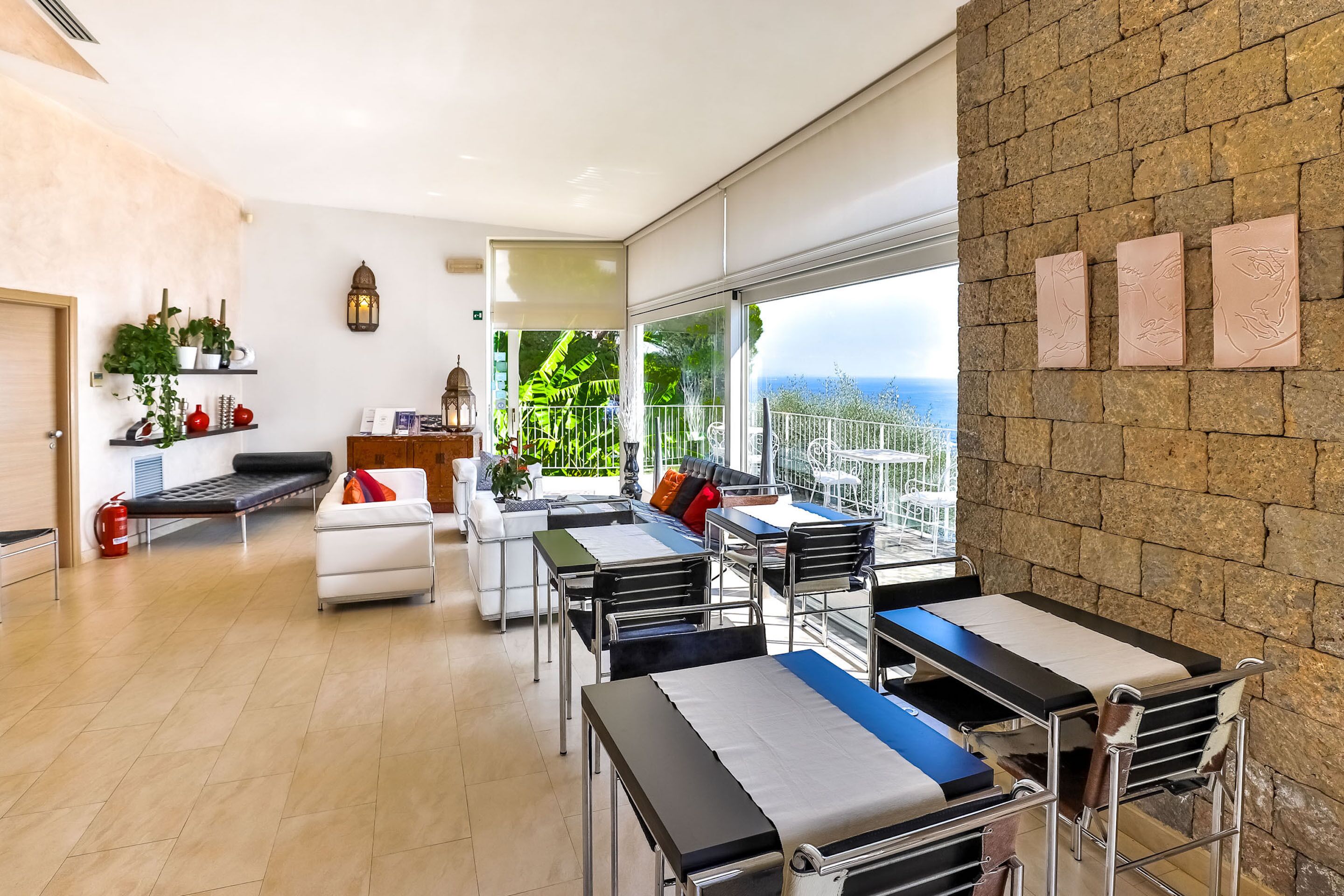 Un ambiente interno moderno con zona pranzo, posti a sedere e vista panoramica tramite ampie finestre.