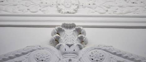 Un detallado molde arquitectónico blanco con diseños ornamentales, incluyendo un motivo floral central y patrones simétricos.