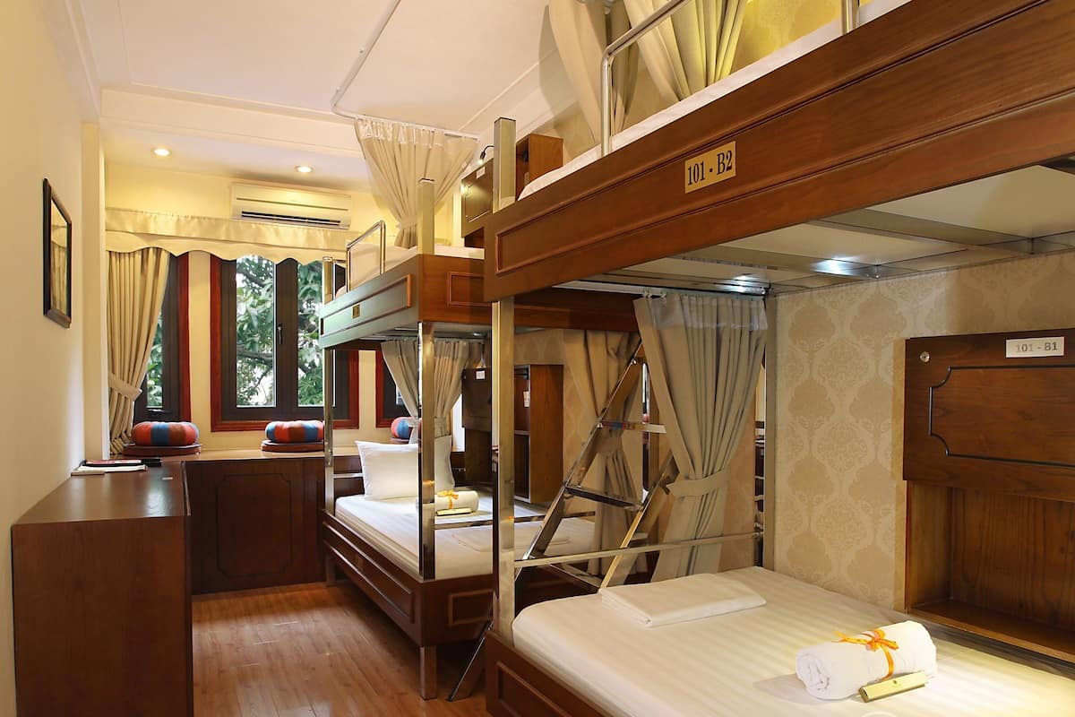 A hotel room with bunk beds, a desk, and a wardrobe.