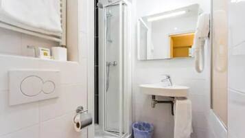 Un bagno moderno con doccia in vetro, lavandino bianco e specchio.