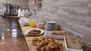 Un bufé de desayuno con cruasanes, pan y zumo.