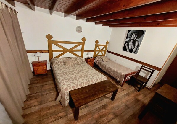 Quarto com duas camas, móveis de madeira, mesa de cabeceira, luminária e quadro na parede.