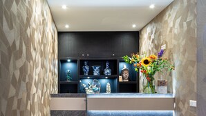 Zona de recepción con mostrador de mármol oscuro, jarrones con motivos azules y blancos, y una decoración floral.