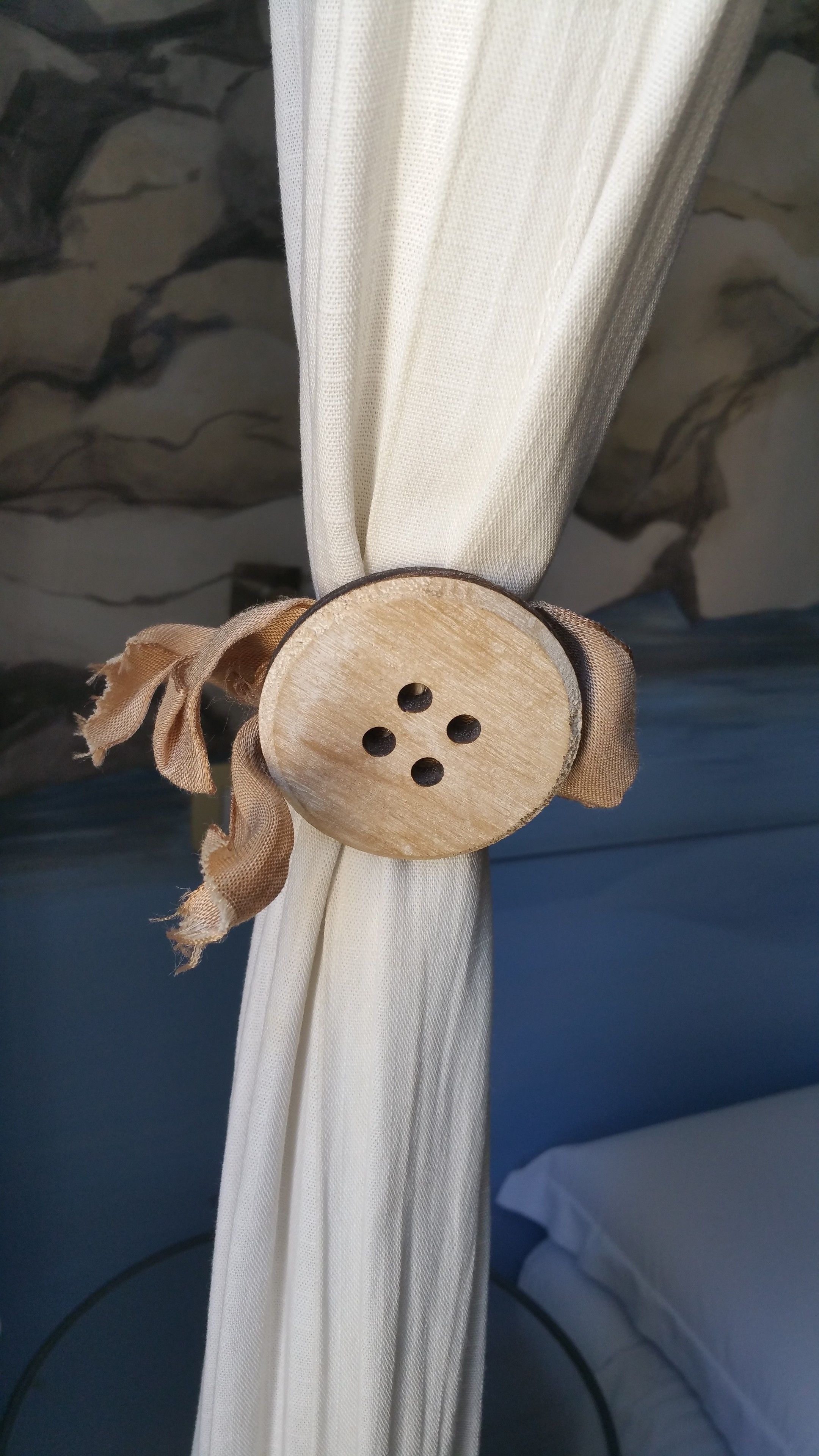 A curtain with a wooden button and tassel detail.