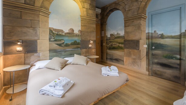A bedroom with a large bed, two nightstands, and a mural of a landscape. - Suites Trastevere (Rome)