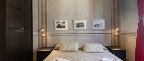 A hotel room with a large bed, two nightstands, a wardrobe, and three framed pictures on the wall.