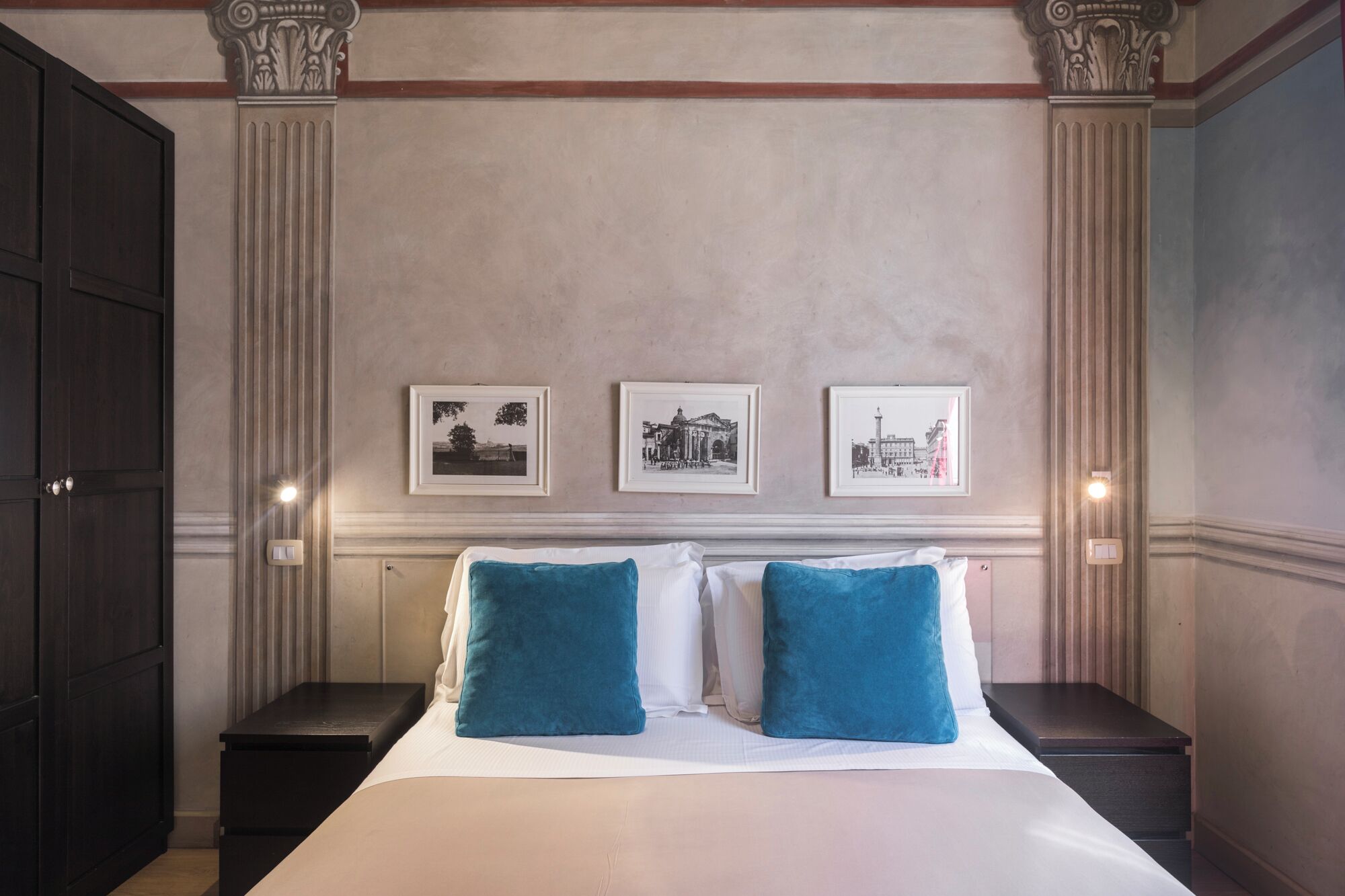 A hotel room with a large bed, two nightstands, and three framed pictures on the wall.