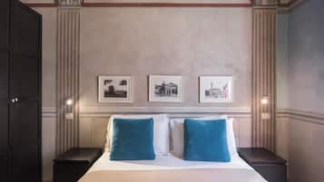 Una habitación de hotel con una cama grande, dos mesitas de noche y tres cuadros en la pared.