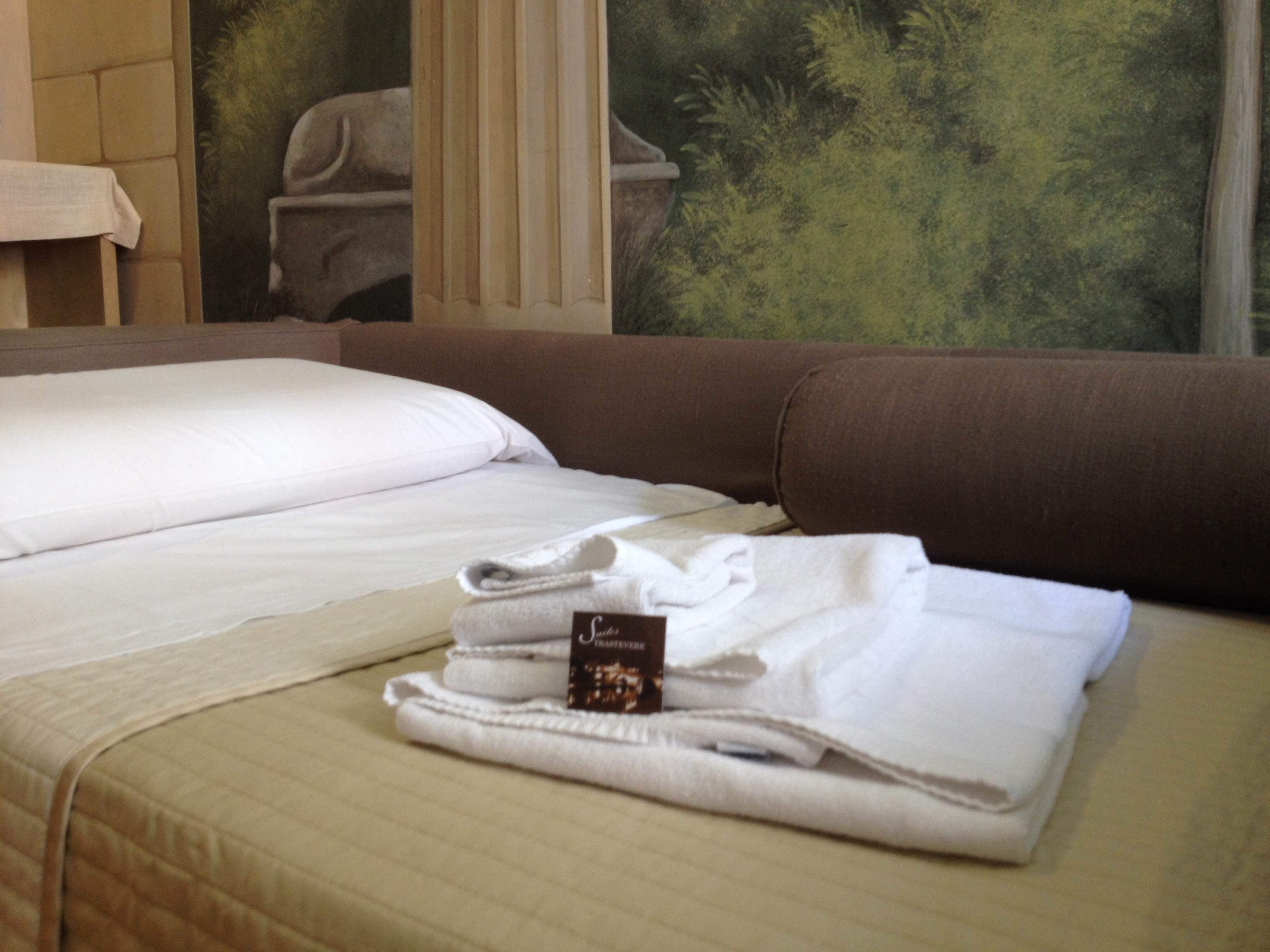 Un lit bien fait, avec des draps blancs et une serviette pliée posée sur le dessus.