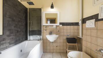 A bathroom with a bathtub, sink, toilet, and a shower area.
