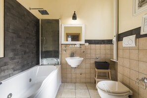 A bathroom with a bathtub, sink, toilet, and a shower area. - Suites Trastevere (Rome)