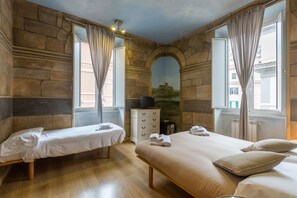 A hotel room with two beds, a dresser, and a television. - Suites Trastevere (Rome)