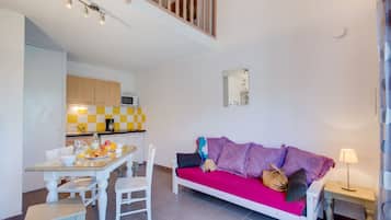 A compact living space with a kitchenette, a dining area, and a sofa.