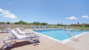 Une piscine avec des chaises longues et un espace délimité par une clôture.