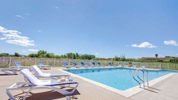 Una piscina al aire libre de temporada, sillones reclinables de piscina