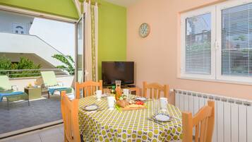 Un comedor con una mesa preparada para dos personas, un televisor y vistas al balcón.