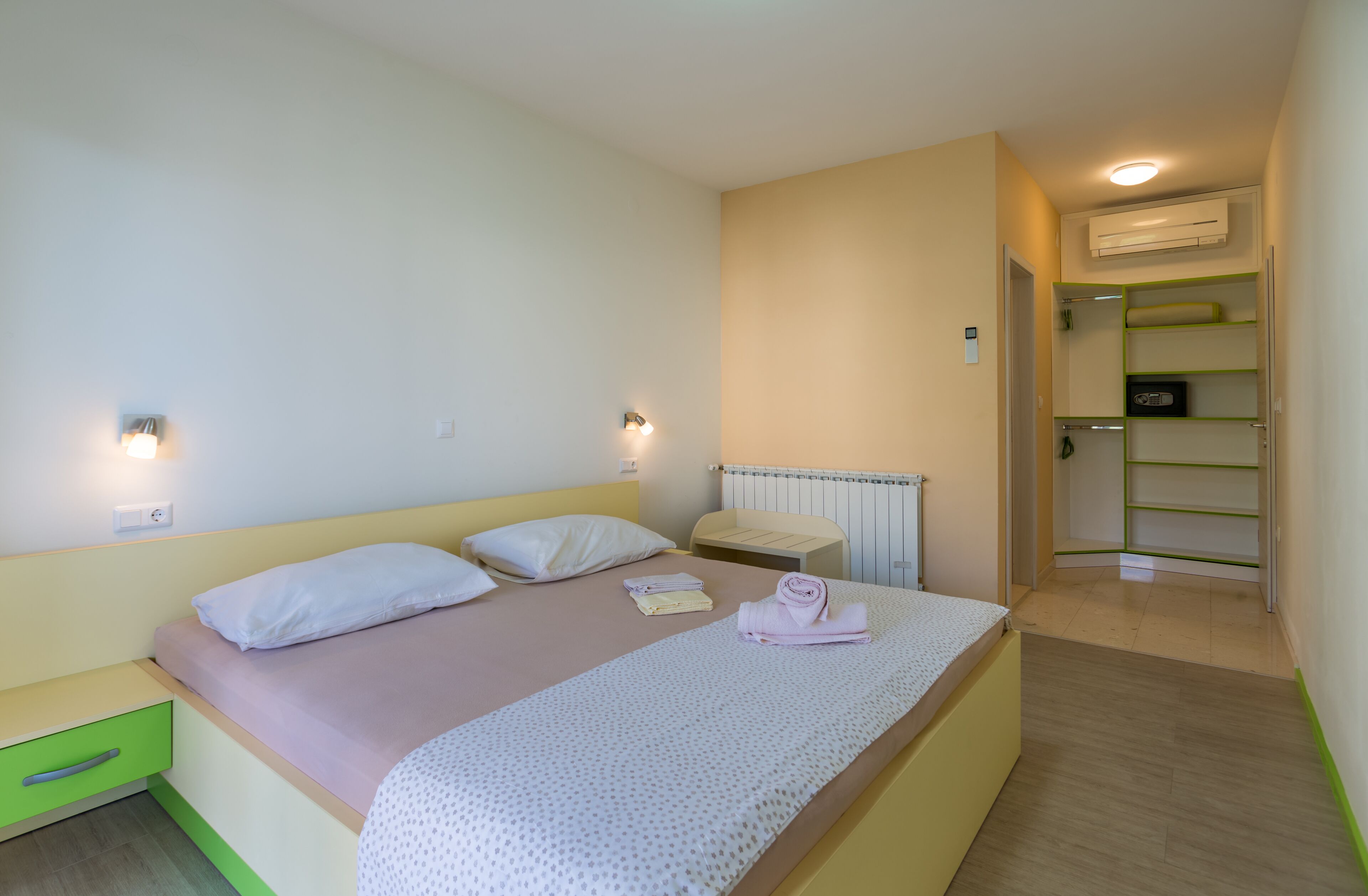 A bedroom with a bed, bedside tables, a radiator, and a wardrobe.