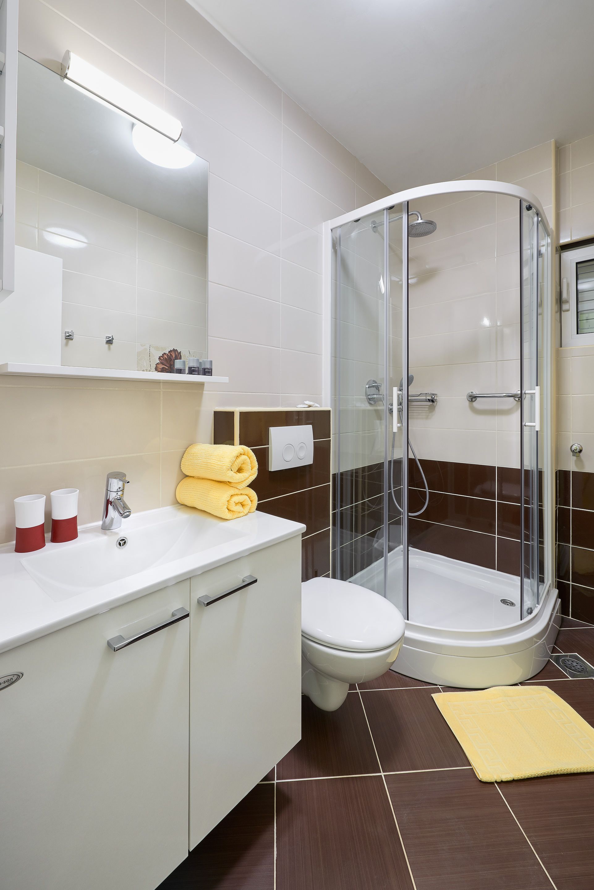 Ein modernes Badezimmer mit einer Duschkabine, einem weißen Waschbecken mit Spiegel darüber und einer Toilette.