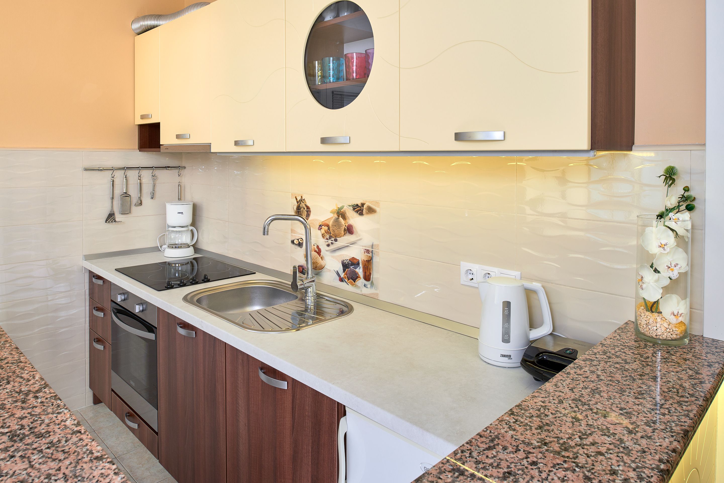 A modern kitchen with a granite countertop, stainless steel sink, and built-in oven.