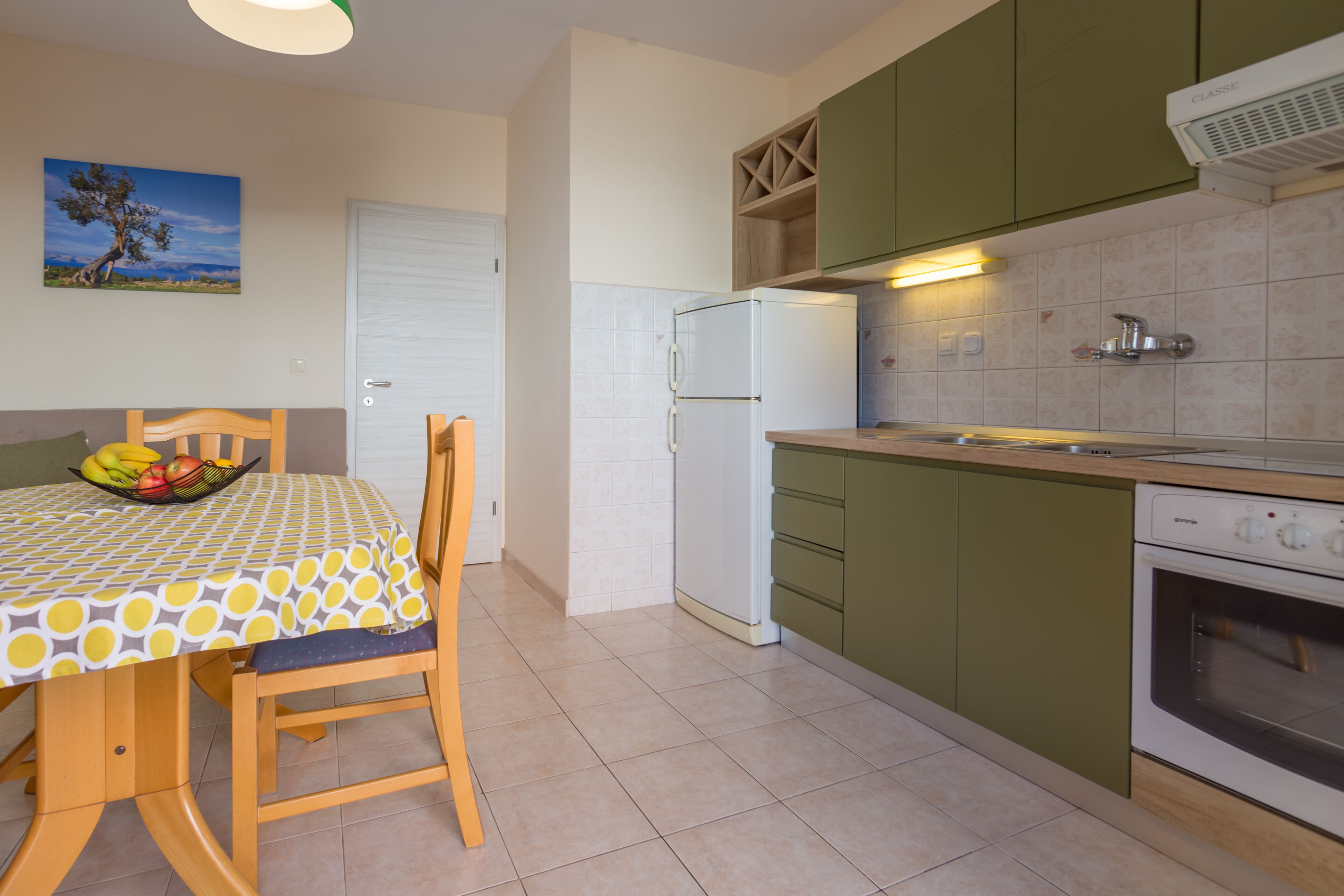Una cocina con una mesa de comedor, sillas, un refrigerador, estufa y armarios.