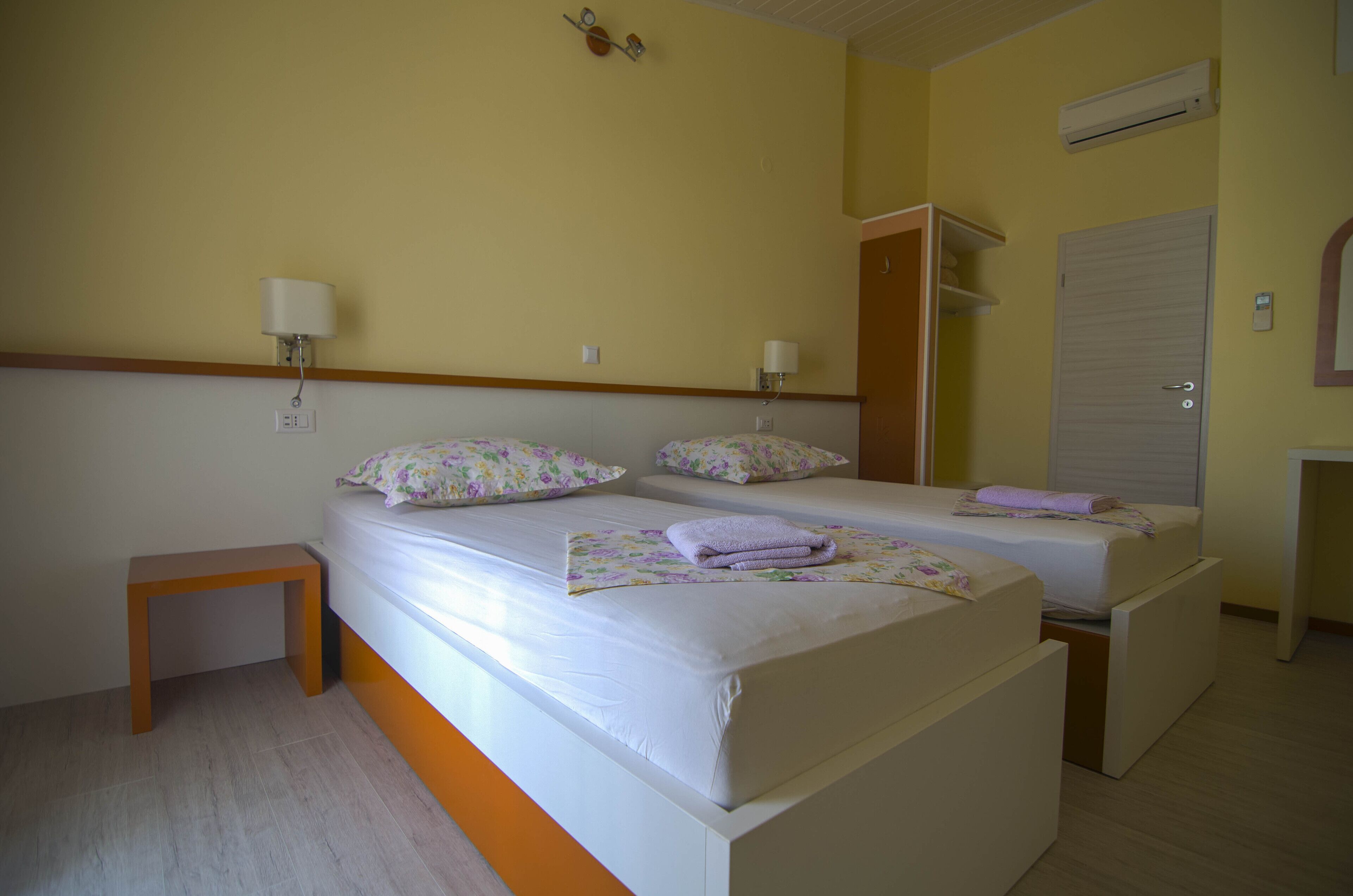 Une chambre avec deux lits, une table de chevet, une armoire et un appareil de climatisation.