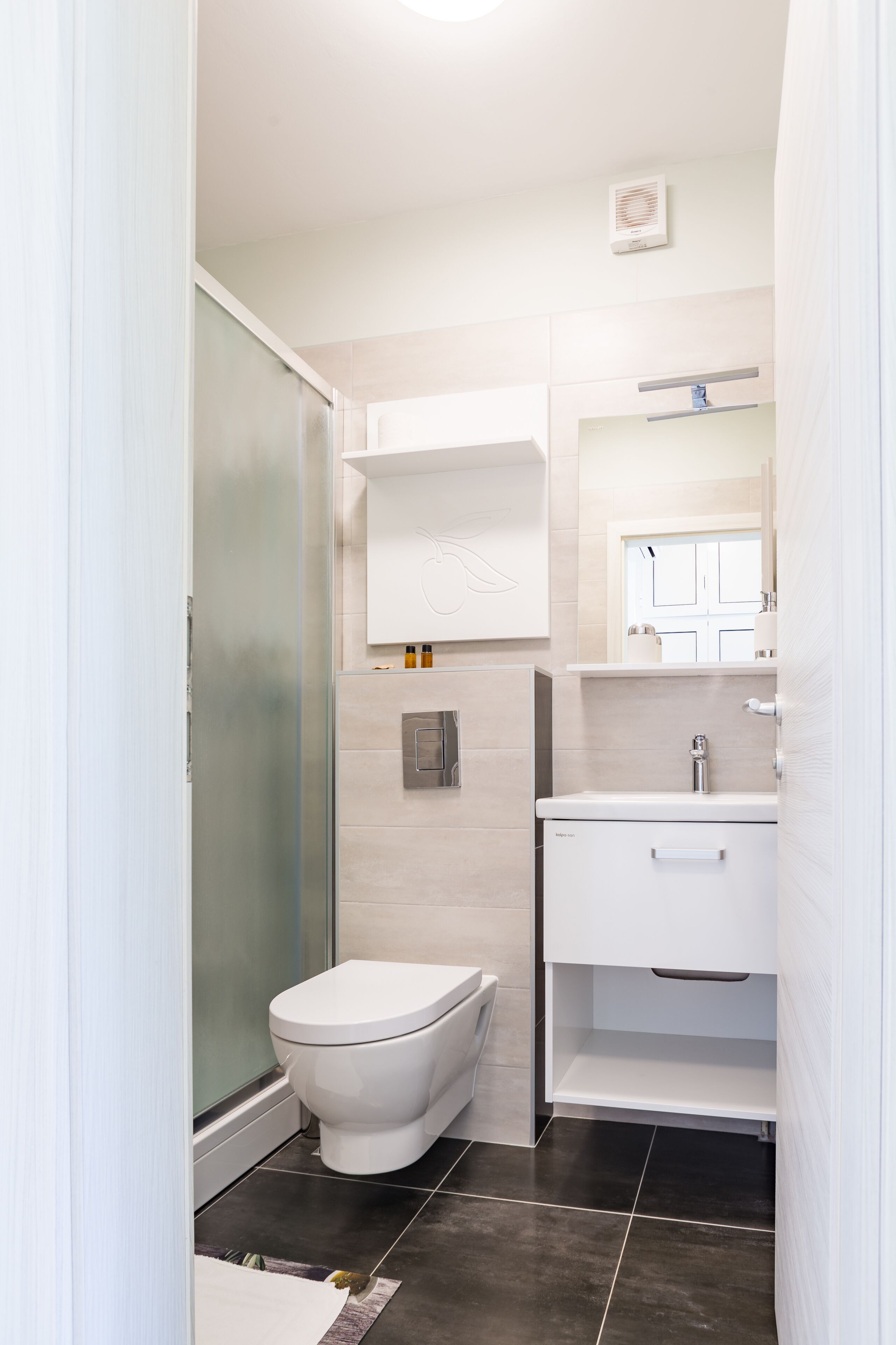 A modern bathroom with a toilet, a shower, and a sink.