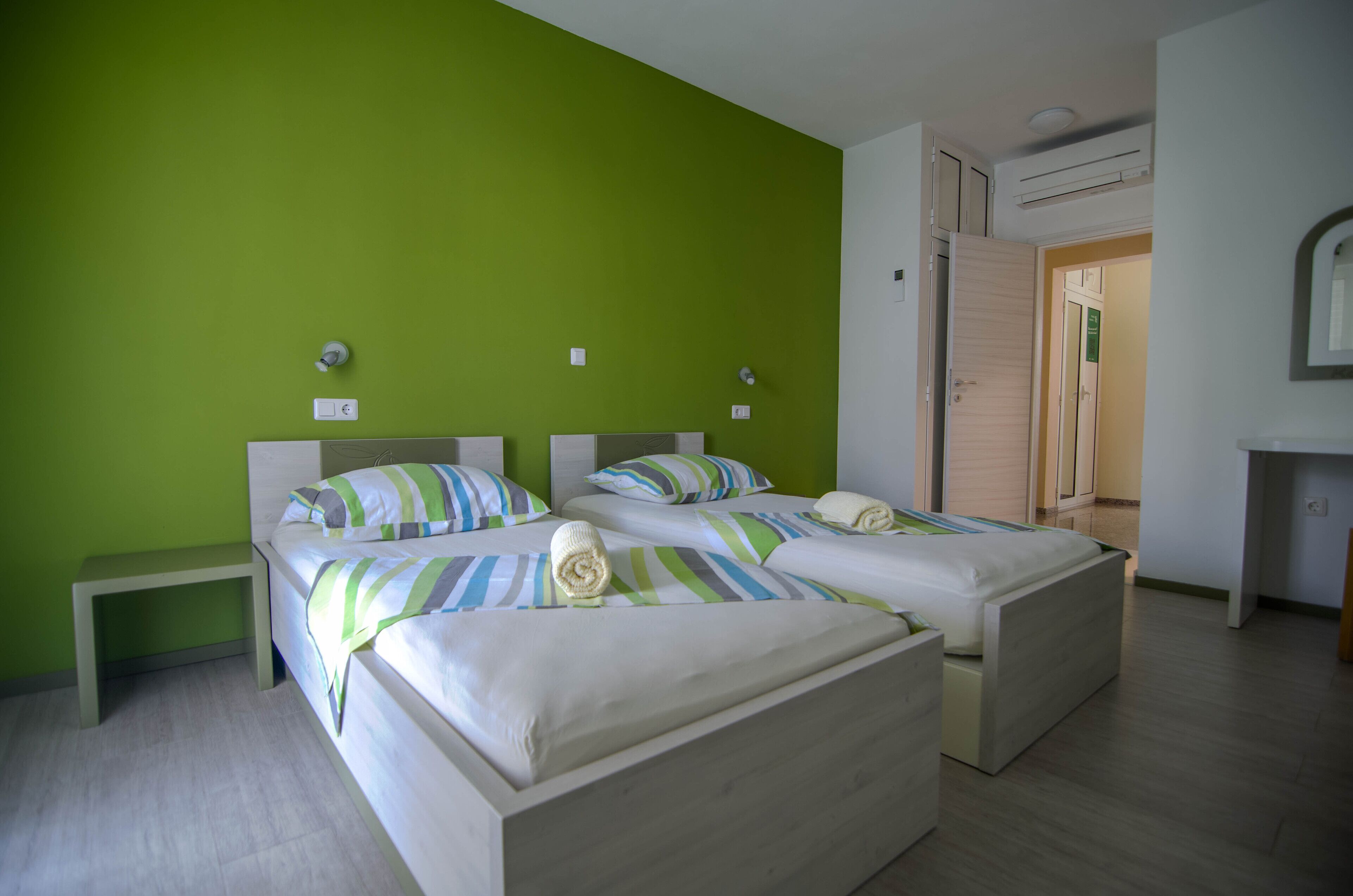 Una habitación con dos camas, una mesita de noche pequeña y un espejo en la pared.