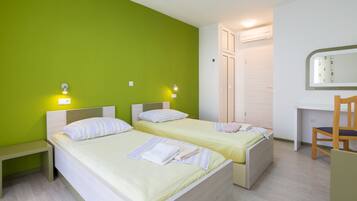 Ein Zimmer mit zwei Betten, einem Schreibtisch und einem Stuhl.