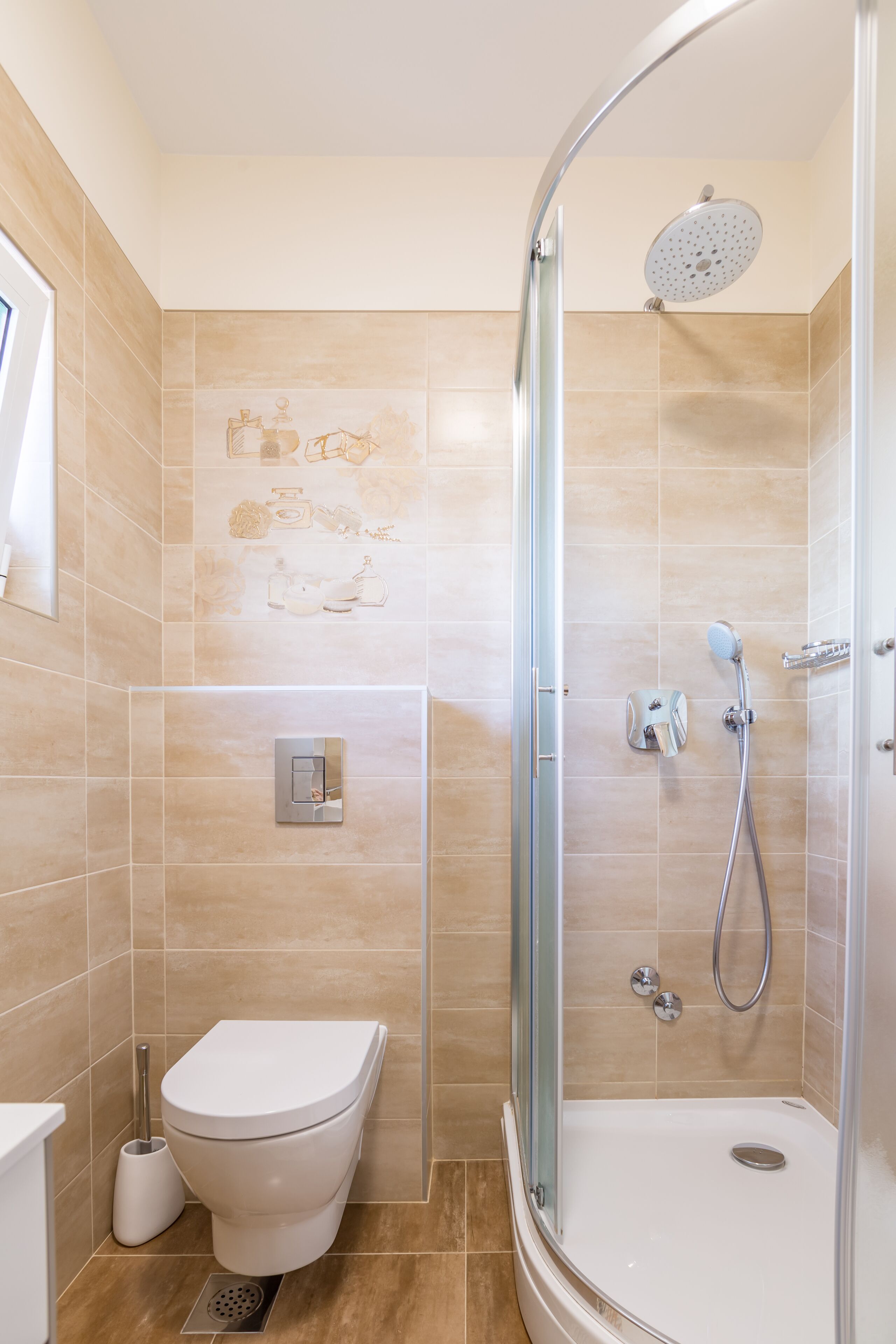 A bathroom with a toilet, a shower with a glass door, and beige tiled walls.