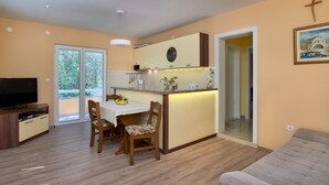 A modern kitchen with a dining area, a TV, and a sofa.