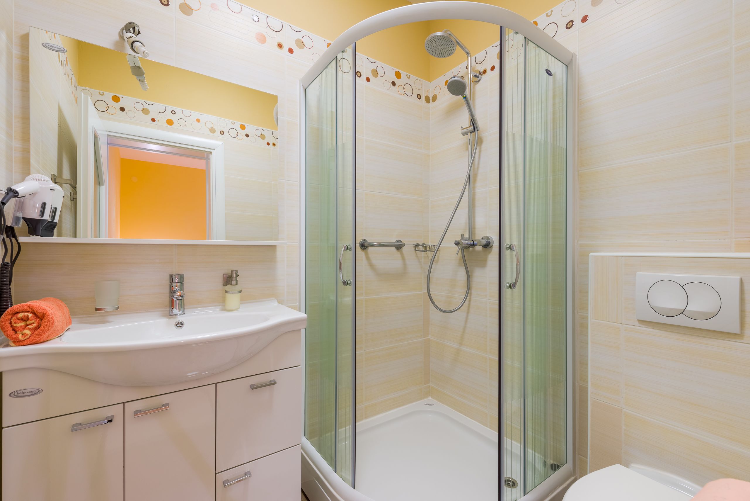 A bathroom with a glass-enclosed shower, a sink with a mirror above it, and a towel on the counter.