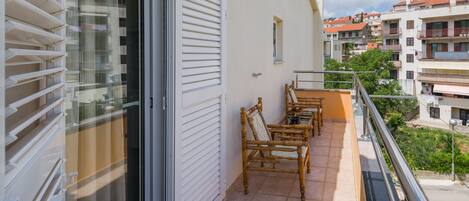 A balcony with a sliding door, a small table, and two chairs.