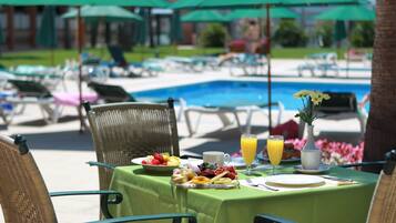 Enjoy a leisurely breakfast amidst a serene poolside setting with a beautifully set table.