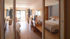 Une chambre d’hôtel équipée d’un lit, d’un bureau, d’une chaise, d’un canapé et d’un balcon avec vue.
