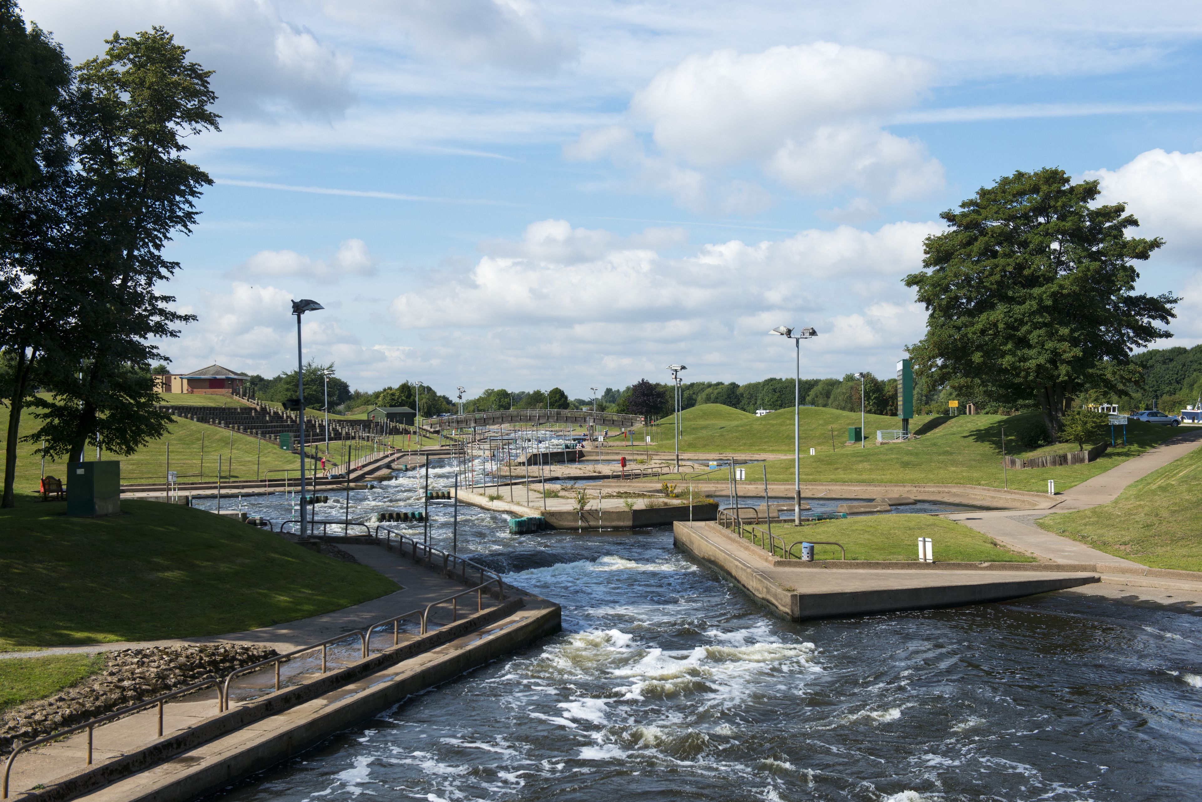 A river with a lock system, surrounded by grassy areas and trees.