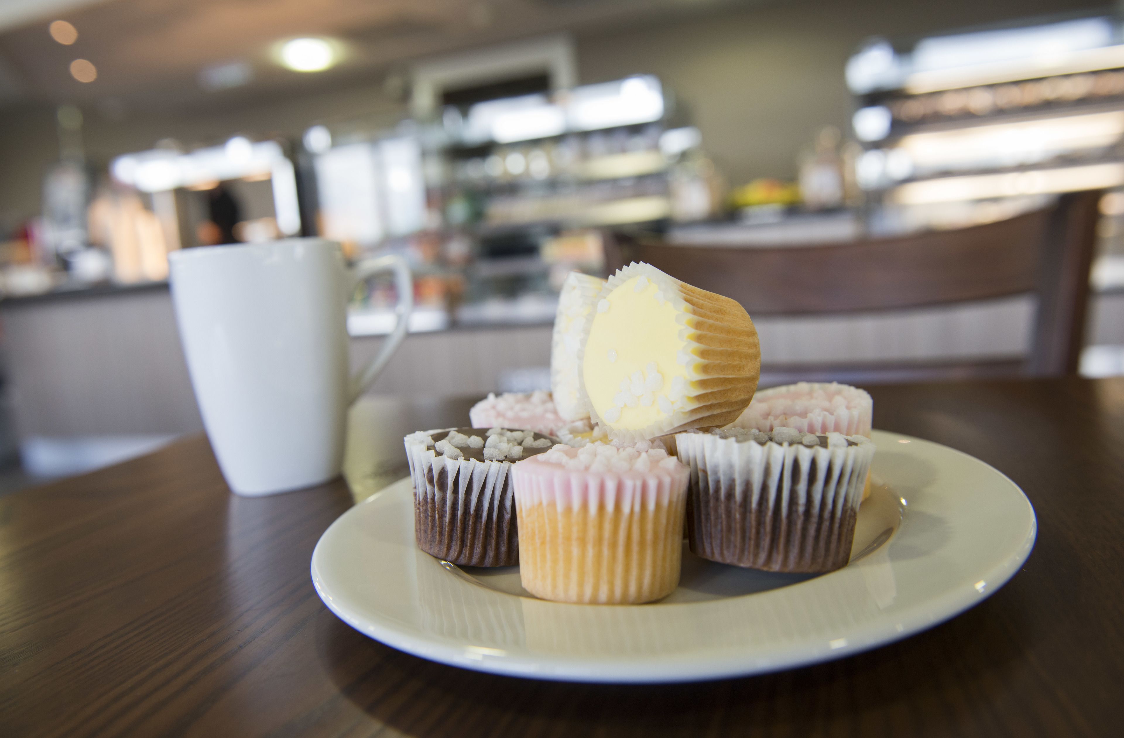 En tallrik med muffins och en vit mugg på ett träbord.