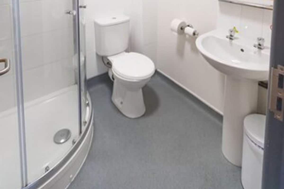 A modern bathroom with a glass-enclosed shower, a white toilet, and a sink with a mirror above it.