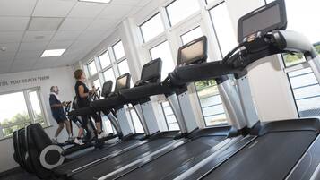 A gym with treadmills, large windows, and a motivational quote on the wall.